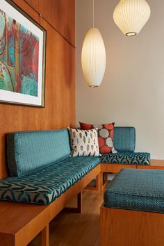 a couch and ottoman in a room with wood paneling on the wall, two lamps hanging from the ceiling