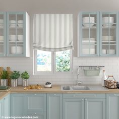 a kitchen with light blue cabinets and white counter tops, along with a window covered in roman shades