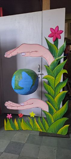 two hands reaching for the earth in front of a refrigerator with flowers and leaves painted on it