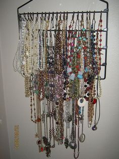 a bunch of necklaces are hanging on a wall next to a door with a hook