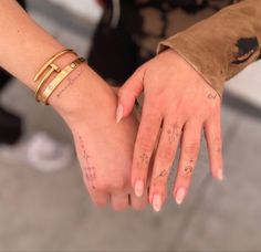 two people holding each other's hands with tattoos on their wrists and fingers that read i love you