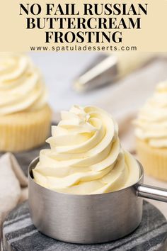 a cupcake with white frosting in a metal pan on top of a table