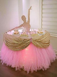 a pink and gold cake table with a dancer on top