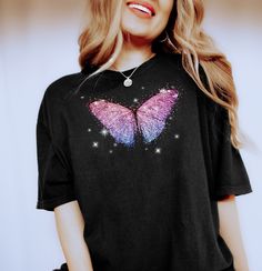 We can't get enough of this magical butterfly tee! Reminiscent of our favorite 90s tees as kids, this colorful shirt will be sure to transport you to another time. Features a beautiful butterfly graphic surrounded by magical sparkles!     Please size up to wear the for the oversized fit / tunic fit! We love Comfort Colors! A Unisex tee that's a perfect fit for every body. Soft and relaxed crewneck that fits like a well-loved favorite. ✦ PRODUCT INFO ✦ ▸ All items are printed just for you using water based eco-friendly & biodegradable inks.  ▸ 100% ring-spun cotton.  ▸ Sewn-in label. ▸ Please note: Colors may differ slightly in person than on a monitor or phone. ✦ CARE INSTRUCTIONS ✦ ▸ Machine wash cold, inside-out on a gentle cycle with a mild detergent and like colors. ▸ Tumble dry on low Graphic Tee With Butterfly Print For Streetwear, Trendy Short Sleeve T-shirt With Butterfly Print, Summer Fairy Grunge T-shirt With Crew Neck, Black Fairy Grunge T-shirt For Summer, Fairy Grunge Graphic T-shirt For Summer, Pink Short Sleeve T-shirt With Butterfly Print, Casual Pink T-shirt With Butterfly Print, Multicolor Short Sleeve T-shirt With Butterfly Print, Cute Butterfly Print Crew Neck T-shirt