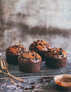 three chocolate muffins cooling on a wire rack next to a bowl of peanut butter