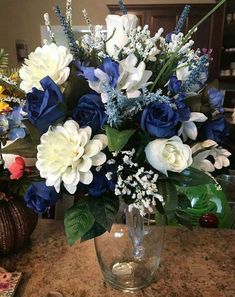 a vase filled with blue and white flowers on top of a marble counter next to a mirror