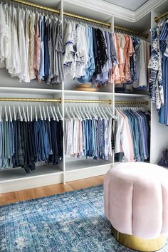 an organized closet with clothes hanging on shelves and a footstool in the middle