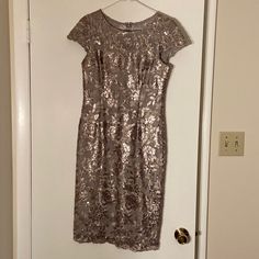 a dress hanging on a door with a hanger in front of it that has a gold sequin pattern