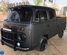 an old black van parked in a parking lot with its lights on and the hood up