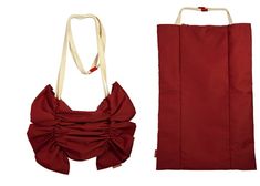 a red bag with a bow on the front and side, next to it's contents