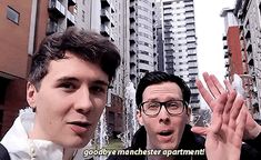 two men standing next to each other in front of tall buildings with the words goodbye manchester apartment