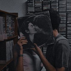 black and white photograph of two people kissing each other in front of bookshelves