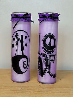 two purple glass jars decorated with black and white designs, one has a skeleton on it