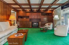 a living room with wood paneling and green carpeted flooring on the walls