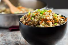 a black bowl filled with vegetables and meat