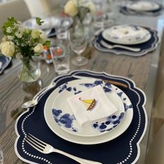 the table is set with blue and white plates, silverware, and vases