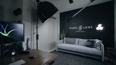 a black and white living room with a couch, television and lights on the wall