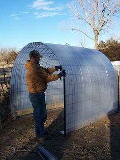 a man standing in front of a large metal structure holding onto a pole and working on it