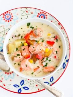 a bowl of soup with shrimp, potatoes and carrots on a colorful floral plate