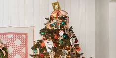 a small christmas tree with ornaments on it next to a quilted wall hanging in the corner