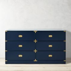 a blue dresser with gold handles and drawers on the bottom, in front of a white wall