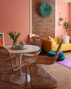 a living room with pink walls and wicker furniture on the floor, along with a yellow couch