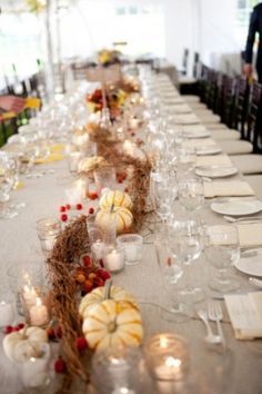 a long table is set up with white pumpkins and candles for an autumn wedding