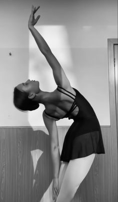 a woman in a black leotard is stretching