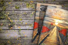 two books sitting on top of a wooden table next to leaves and plants in front of them