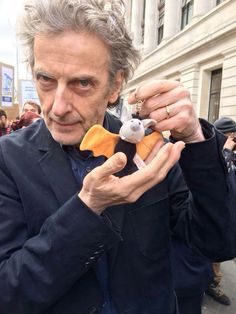 an older man holding a stuffed animal in his right hand and looking at the camera