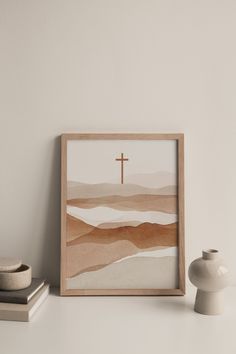 a white vase sitting next to a wooden framed cross