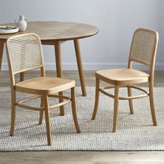 a table and two chairs in a room with a rug on the floor next to it