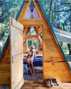 a woman sitting in a small wooden cabin with her feet up on the bed and looking at the camera