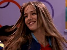 a woman with long hair smiling and wearing a blue jacket on the set of friends