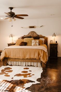 a bedroom with a bed, ceiling fan and cow hide rug on the floor in front of it