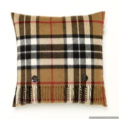 a brown and black plaid pillow with fringes on the front, sitting on a white surface