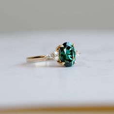 a green and white diamond ring sitting on top of a table