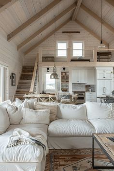 a living room filled with white furniture and lots of wooden beams on the ceiling,