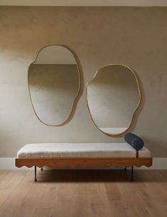 a bench sitting in front of two mirrors on the wall