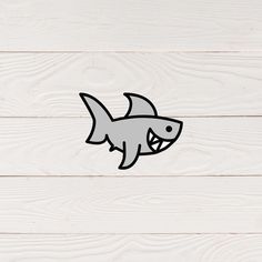 a sticker of a shark with its mouth open on a white wooden background,