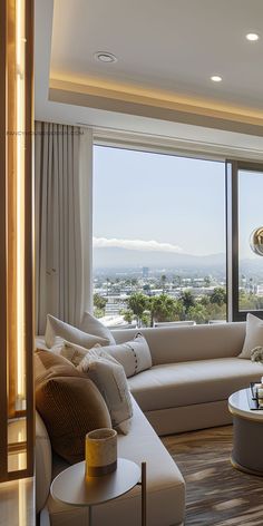 a living room filled with furniture and a large window overlooking the cityscape in the distance