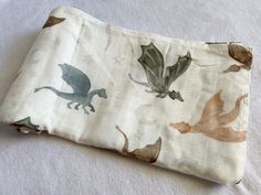 an image of a cloth bag with dinosaurs on the front and back side, sitting on a bed