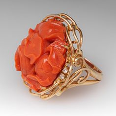 This fantastic vintage ring is centered with a carved floral design coral that is set into four-prongs. The coral is bordered with four (4) prong set round brilliant cut diamonds. The ring measures 25.9mm at the top, rises 12.7mm above the finger, tapering to 2.5mm wide and 0.8mm thick at the base of the shank. It is currently a size 4.5. Elegant Coral Rings For Anniversary, Coral Elegant Wedding Rings, Elegant Coral Wedding Rings, Elegant Carved Orange Jewelry, Elegant Orange Carved Jewelry, Brand Presentation, Coral Ring, The Coral, February Birth Stone