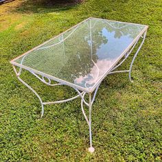 a glass table sitting on top of a lush green field