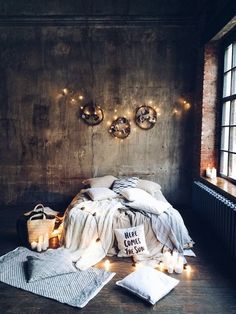 an unmade bed with lights on the wall