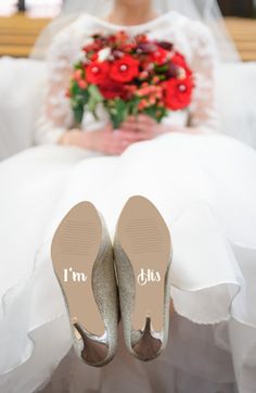 the bride is sitting down with her wedding shoes on and bouquet in front of her