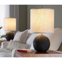 two lamps sitting on top of a table next to a couch