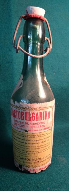 an old metal bottle with a white cap on it sitting on a green tablecloth