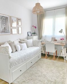 a living room filled with white furniture and pictures on the wall above it's windows