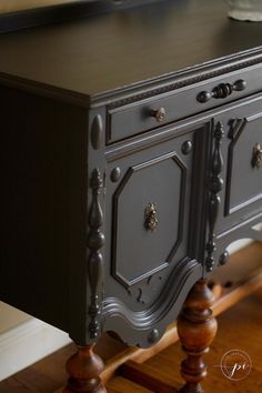 an antique sideboard painted in dark grey with wood trimmings and knobs